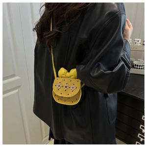 Détail du mini sac jaune gingembre avec fleurs blanches, nœud et pois noirs stylés