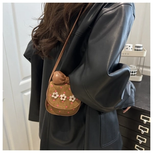 Detailed view of mini brown crossbody bag with pink polka dots and white floral accents
