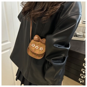 Détail du mini sac bandoulière camel foncé avec broderies fleurs et nœud en cuir marron