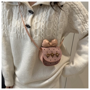 Gros plan d'un mini sac rose avec nœud, pois et décorations florales en peluche