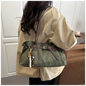 Dettaglio della borsa tote in pelle scamosciata verde scuro con nappe e tracolla marrone