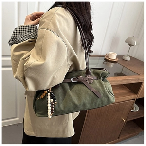 Dettaglio borsa tote in pelle scamosciata verde scuro con tracolla in pelle e perline