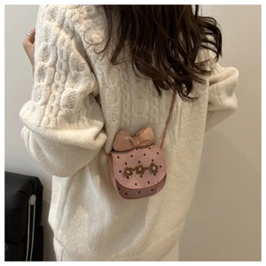 Close-up of pink crossbody bag with polka dots, bows and flowers on white sweater