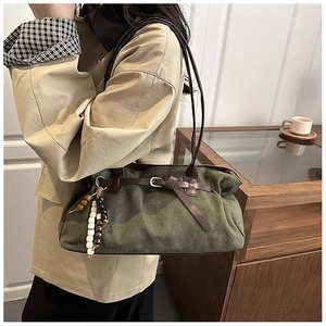 Dettaglio borsa tote in pelle scamosciata verde con cinturini marroni e nappa di perline