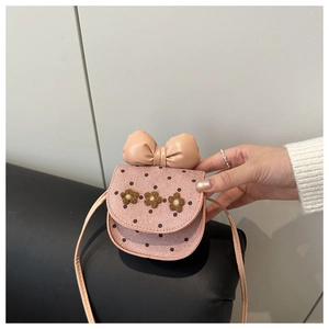 Detail view of pink polka dot crossbody bag with plush flowers and a leather bow