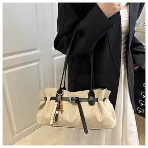 Detail of beige faux suede hobo bag with wood bead tassel and black leather strap