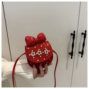Détail d'un mini sac bandoulière rouge à pois avec fleurs et un grand nœud sur le dessus