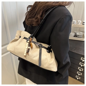 Dettaglio borsa a tracolla beige in pelle scamosciata con cinturino nero e perle di legno