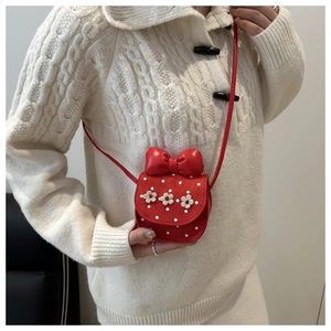 Detail of red mini crossbody bag with a large bow, white polka dots, and floral accents