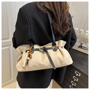 Dettaglio borsa hobo in pelle scamosciata beige con fibbia nera e ciondolo di perline