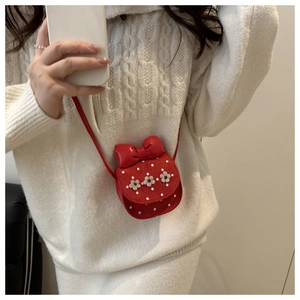 Close-up of a red polka dot mini bag featuring a large bow and white 3D floral accents