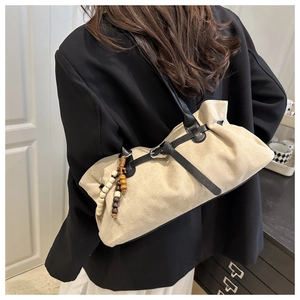 Dettaglio della borsa tote in camoscio beige con nappa in legno e cinturini in pelle nera