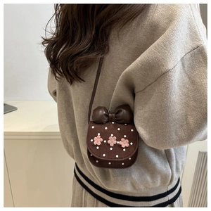 Rear view of model wearing a mini brown polka dot bag with a large bow and pink flowers