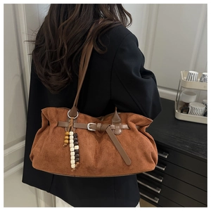 Dettaglio della borsa tote in pelle scamosciata marrone con fibbia e ciondolo in legno
