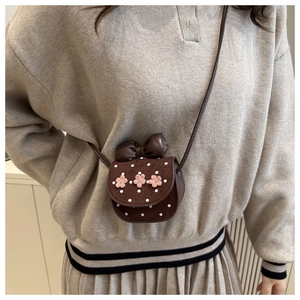Détail d'un mini sac bandoulière marron foncé avec fleurs roses et nœud décoratif
