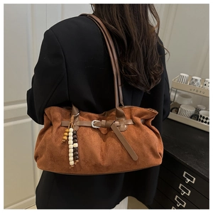 Dettaglio della borsa tote in pelle scamosciata marrone con ciondolo boho in legno