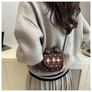 Mini sac bandoulière marron avec fleurs roses et pois blancs porté par un modèle