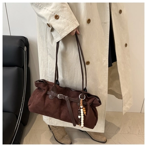 Dettaglio della borsa tote in pelle scamosciata marrone con fibbia e ciondolo in legno