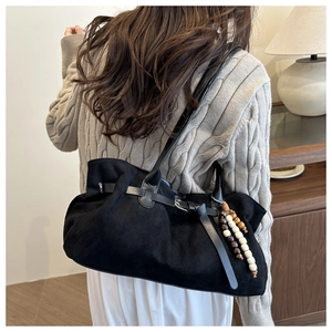 Dettaglio della borsa tote in pelle scamosciata nera con cinturini e ciondolo di perline in legno