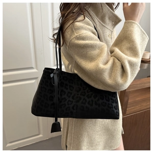 Detail einer schwarzen Tote Bag mit Leopardenmuster kombiniert mit einem beigen Wintermantel