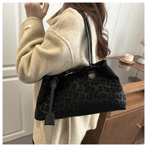 Détail du sac à bandoulière noir à motif léopard porté par le mannequin en situation