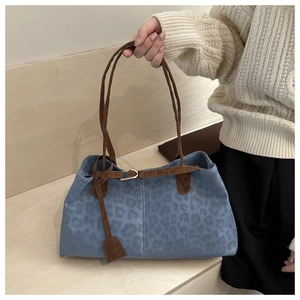 Détail d'un sac cabas à imprimé léopard bleu avec anses en daim marron et boucles en métal