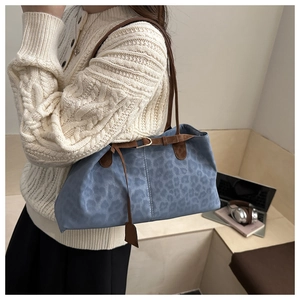 Sac fourre-tout bleu léopard avec anses en cuir marron porté par un mannequin
