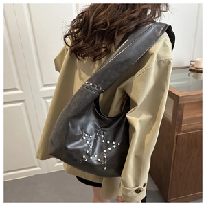 Detail of black underarm bag with silver star studs and wide strap on model
