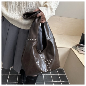 Detail of dark brown leather underarm bag with silver rivet star pattern and wide handle