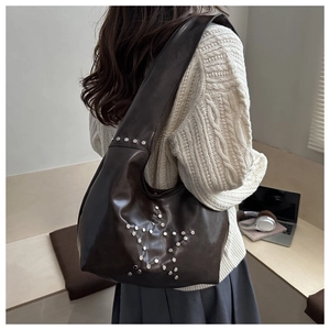 Detail of star-shaped silver rivets on dark coffee vintage leather shoulder bag