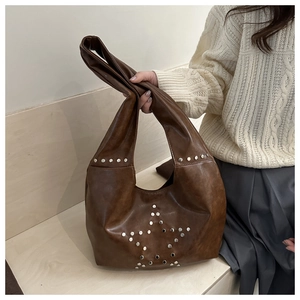Detail view of star-shaped silver studs on dark brown retro leather shoulder bag