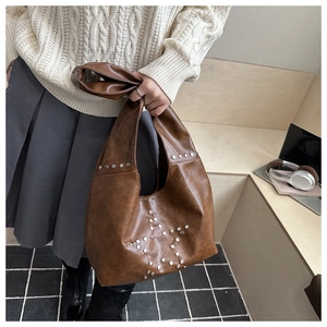 Detail of silver star studs on vintage brown leather tote bag with casual urban styling