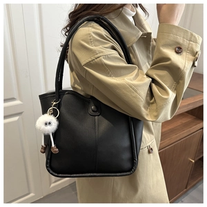 Détail d'un sac cabas en cuir noir avec coutures verticales et breloque peluche