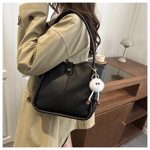 Détail du sac cabas en cuir mat noir avec coutures verticales et breloque en peluche