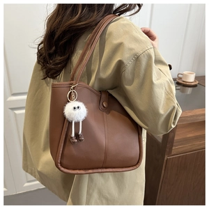 Détail d'un sac cabas en cuir marron avec charme en peluche blanche en intérieur