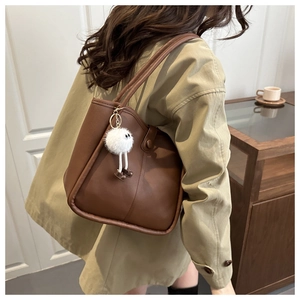 Détail du sac cabas vintage marron avec un adorable porte-clé monstre en peluche blanc