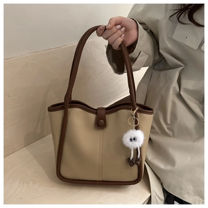 Détail d'un sac cabas vintage avec passepoil contrasté et breloque monstre en peluche
