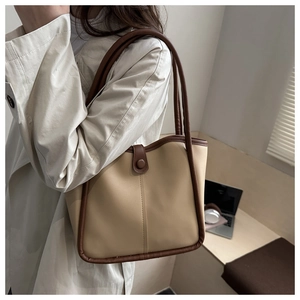 Vista lateral de bolso tote en contraste con hebilla vintage en modelo con gabardina
