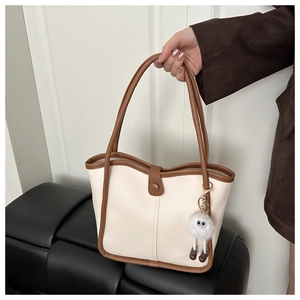 Détail du sac cabas beige avec bordure marron et pendentif monstre en peluche doux