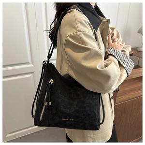 Detail of black faux suede tote bag with side fringe zipper and fashion slogan