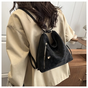 Detailed back view of a black matte crossbody bag with gold zippers worn by a model