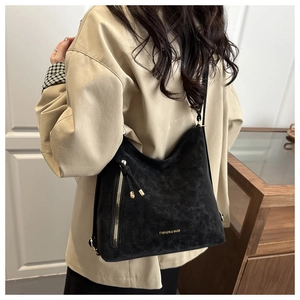 Detail of black hobo bag with gold zipper and metal fashion branding lettering