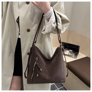 Detail of dark brown tote bag with vintage texture, metal zipper, and tassel decoration
