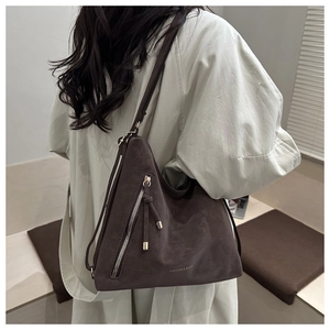 Detail view of dark brown frosted tote bag with metal zipper and long tassels for daily commute