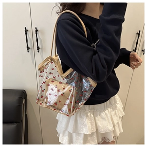 Dettaglio della borsa tote trasparente in PVC con stampa ciliegia e pochette interna su modella