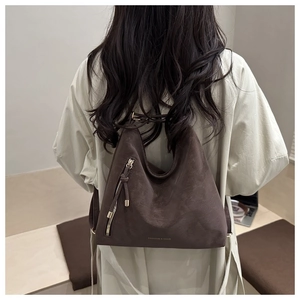 Detail of coffee brown suede tote bag with tassel zipper and fashion print on model