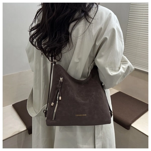 Detail of dark brown suede shoulder bag with tassel zipper and fashion print