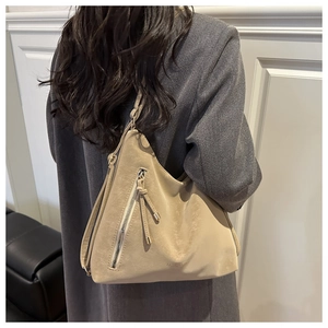 Detail of beige tote bag featuring vintage texture and diagonal metal zipper with tassel