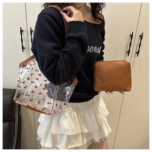 Detail of transparent cherry print tote with brown leather trim and matching inner pouch