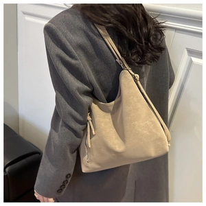 Detail of khaki suede leather tote bag featuring side metal zipper and tassel accent